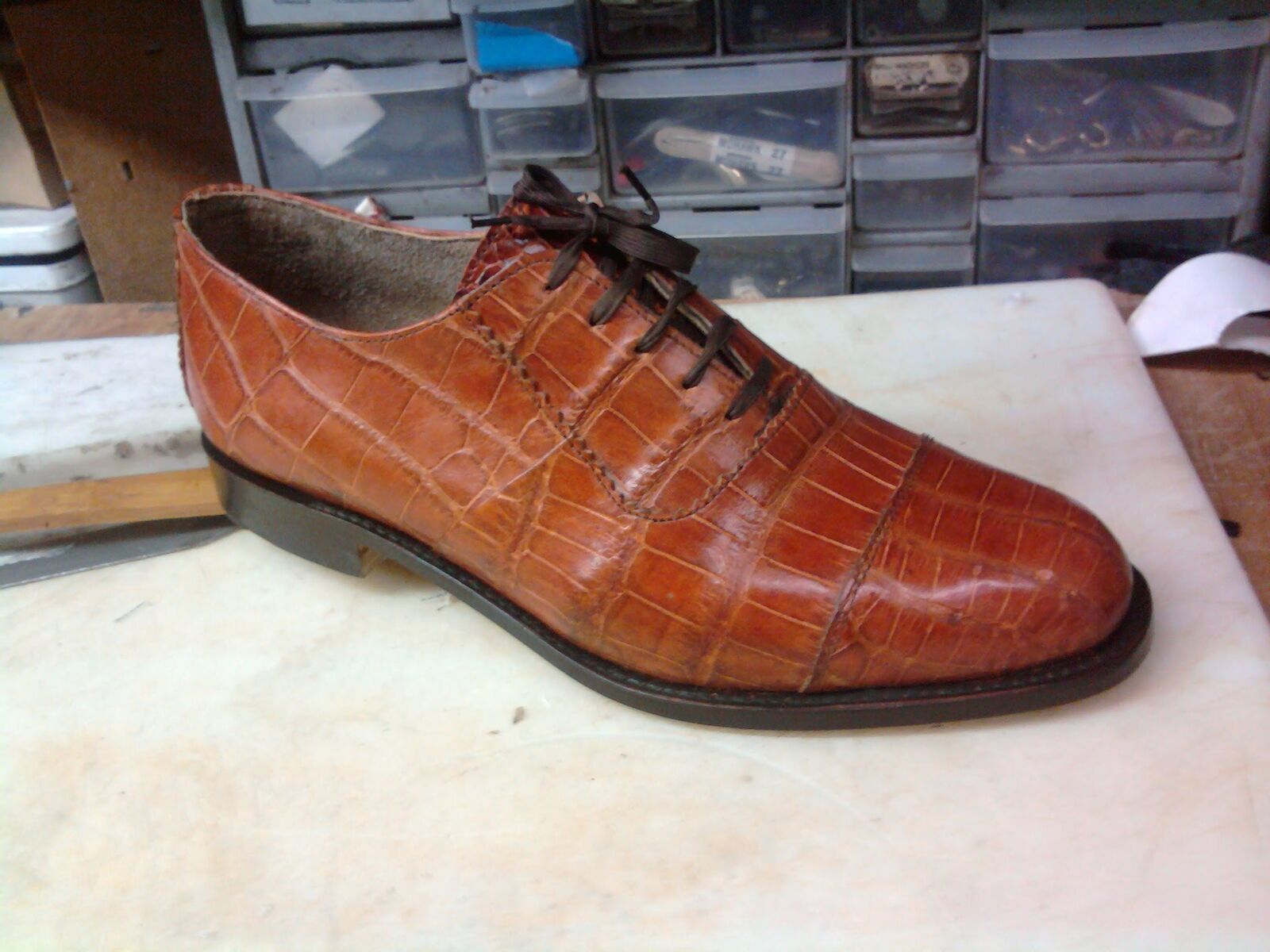 Cognac crocodile cap-toe oxford on the workbench, hardware drawers behind